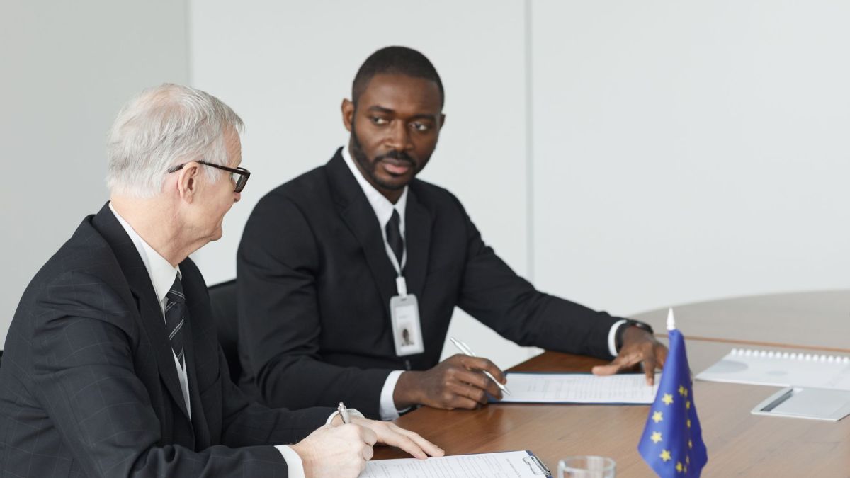 Two businessmen in formal suits discussing at a conference table.