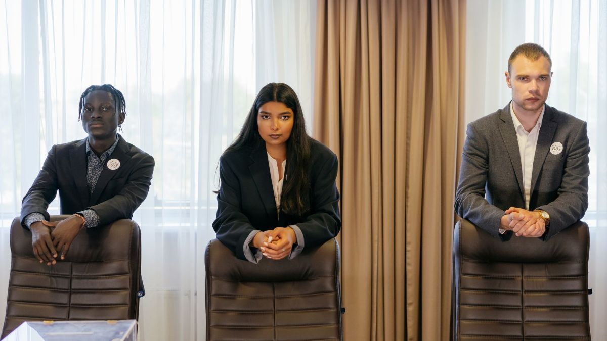 Three diverse professionals in suits in a conference room, expressing confidence and teamwork.