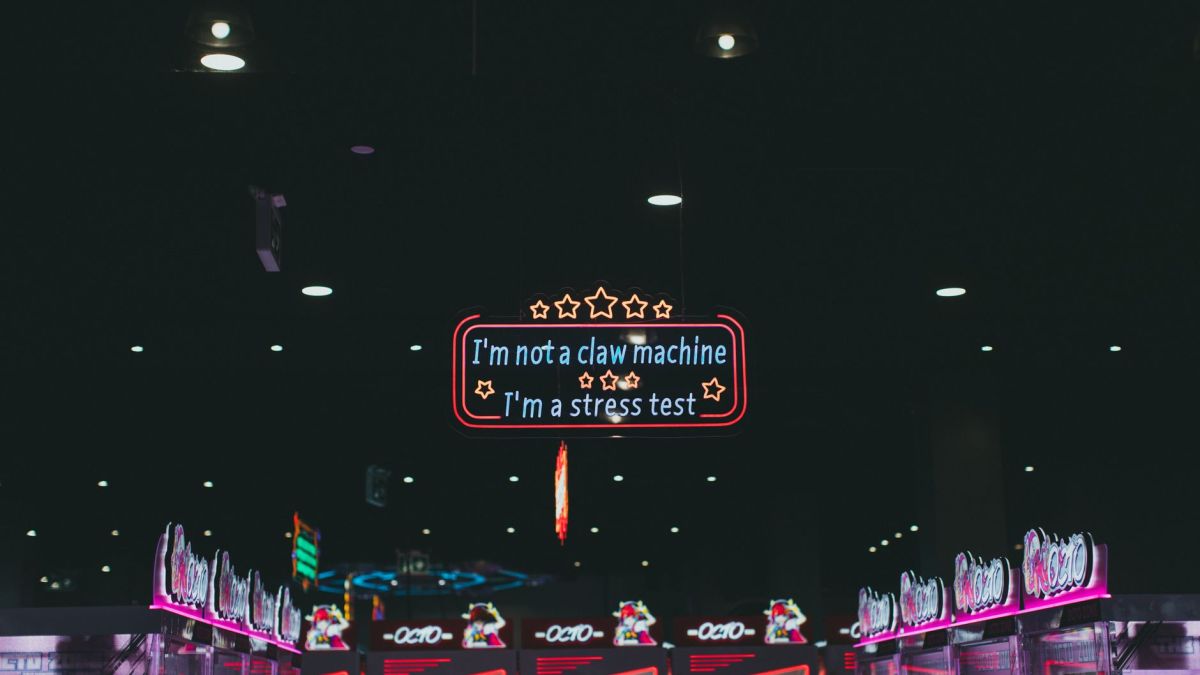 Colorful neon sign in an illuminated arcade, featuring claw machines.