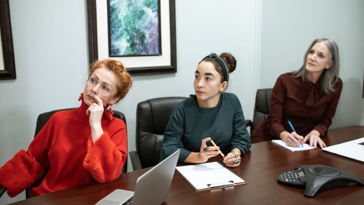 A group of women actively engaged in a collaborative business meeting at a modern office.
