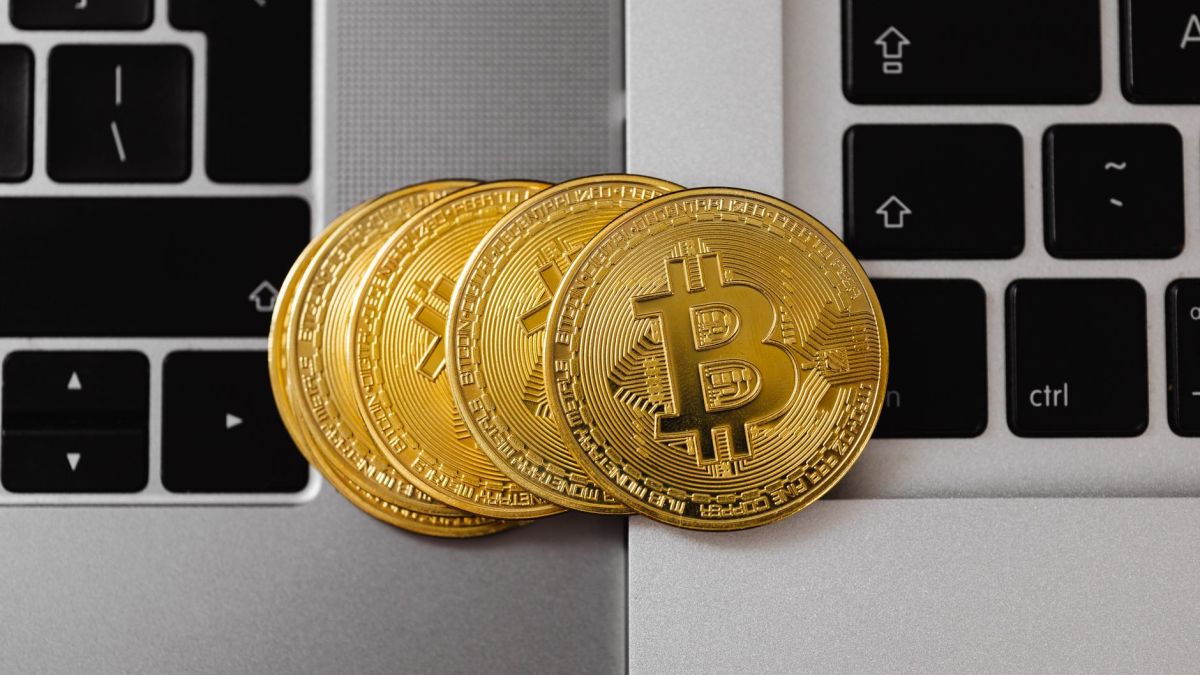 Close-up of Bitcoin coins resting on two laptop keyboards, representing digital currency and technology.