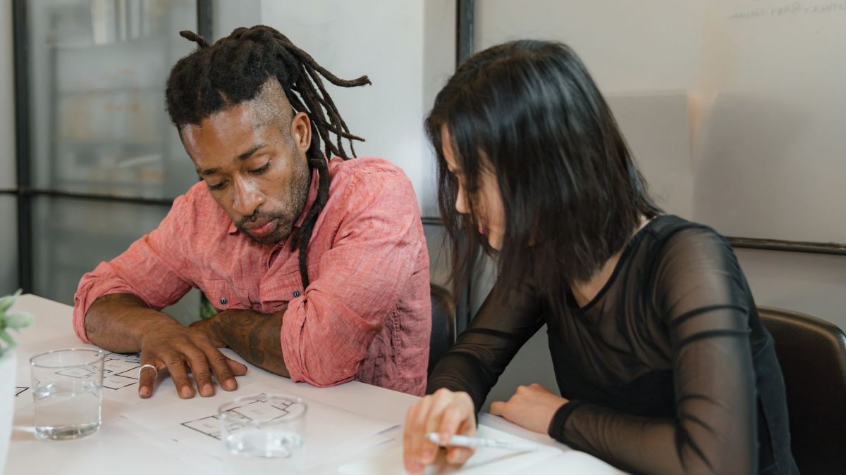 Two colleagues collaborate on design plans in a modern office setting. Focus on teamwork.