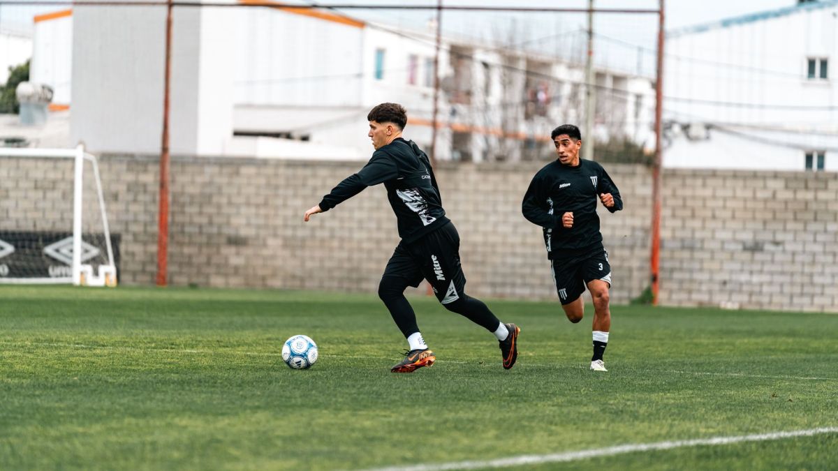 Two soccer players training intensely on a green field during daytime.