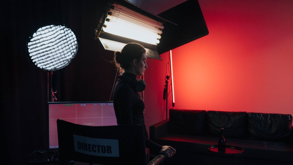 A director in a studio setting with lighting and equipment, creating a cinematic atmosphere.