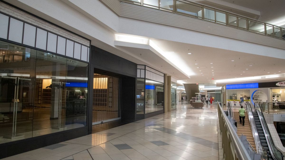 Spacious and contemporary mall interior with closed stores and escalator.