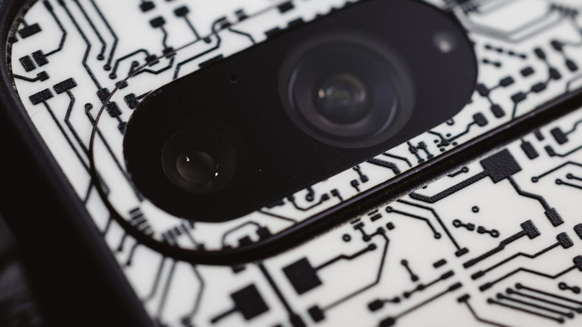 Macro shot of an electronic circuit design around a smartphone camera lens, showing intricate details.