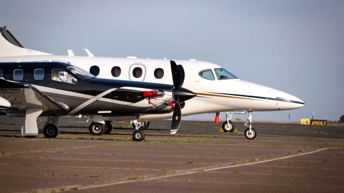 Luxury private aircraft parked on an airport tarmac, ready for departure under clear blue skies.