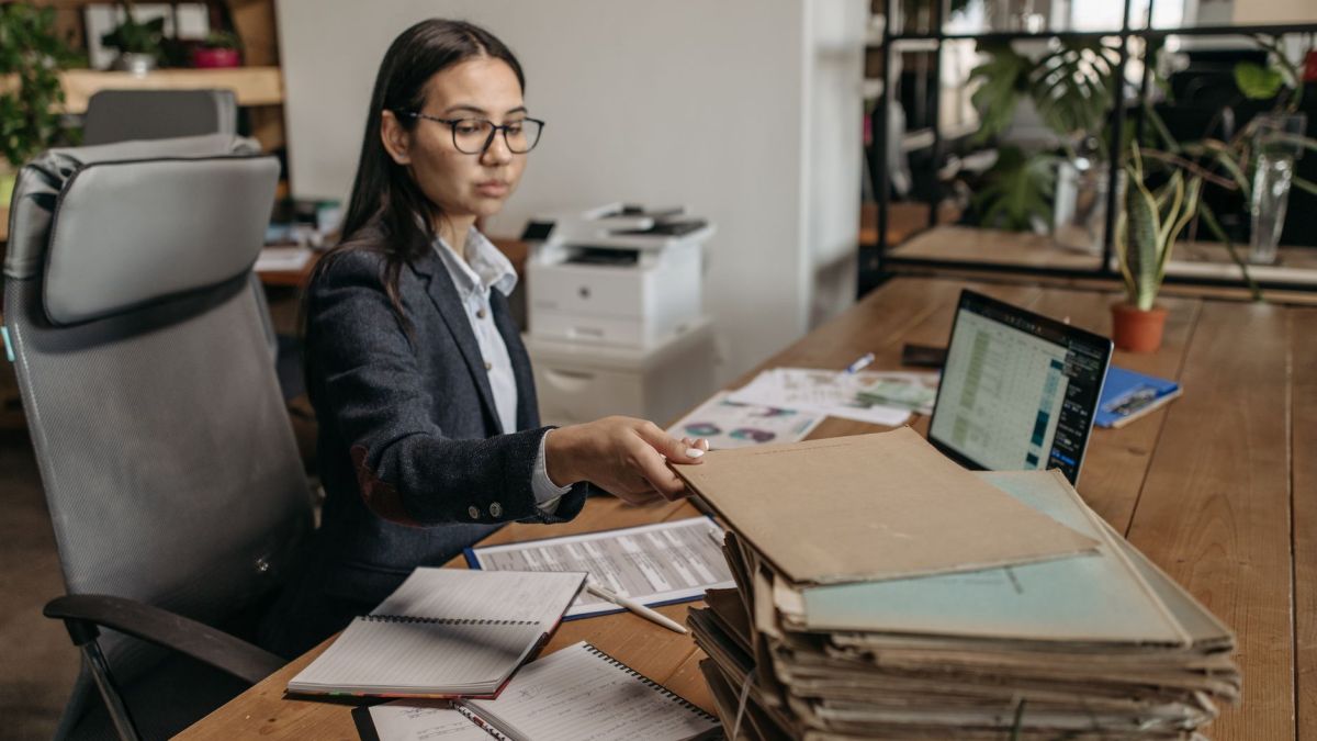 Businesswoman working at a wooden desk with documents and laptop in a modern office.