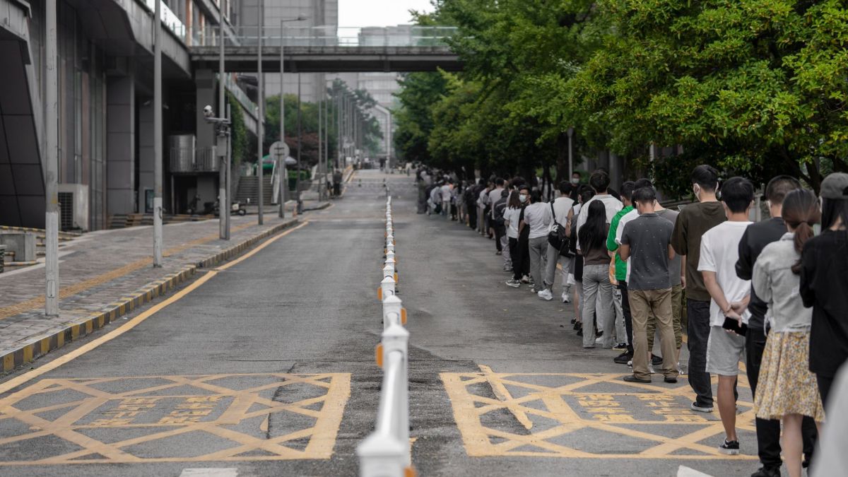 A large group of people lined up along a city street, highlighting urban planning and human patience.