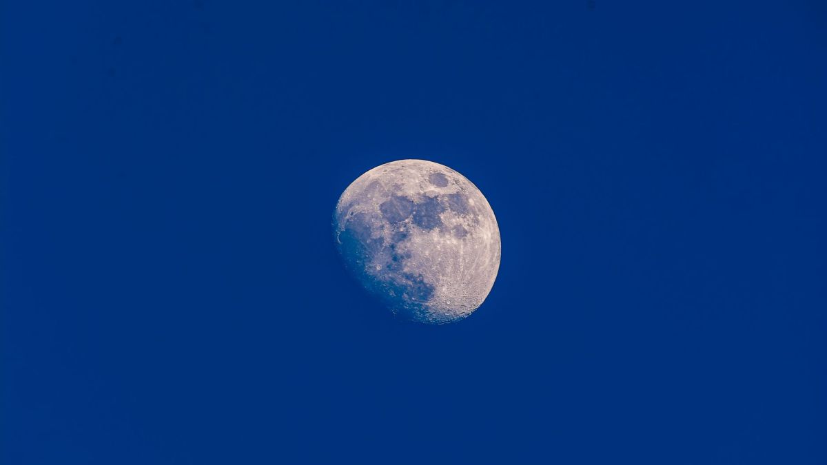 A clear view of the waxing gibbous moon set against a vibrant blue sky, showcasing lunar details.