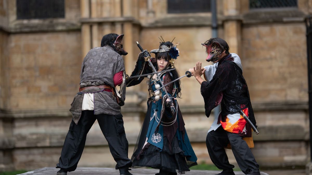 Intense cosplay battle with swords in a medieval outdoor setting.
