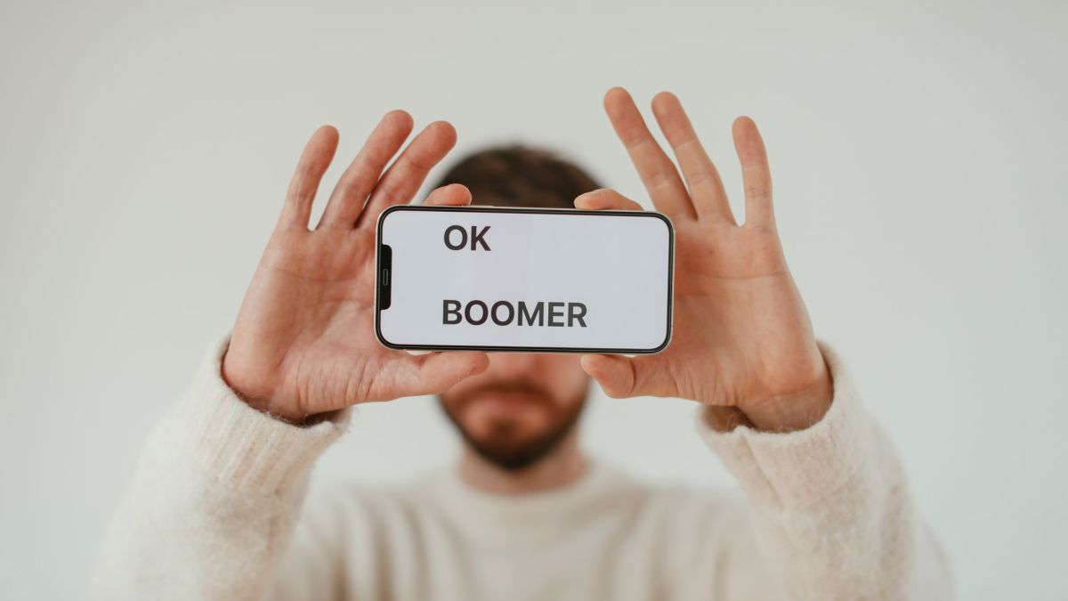 A man holding a smartphone with 'OK Boomer' text, emphasizing generational themes and internet culture.