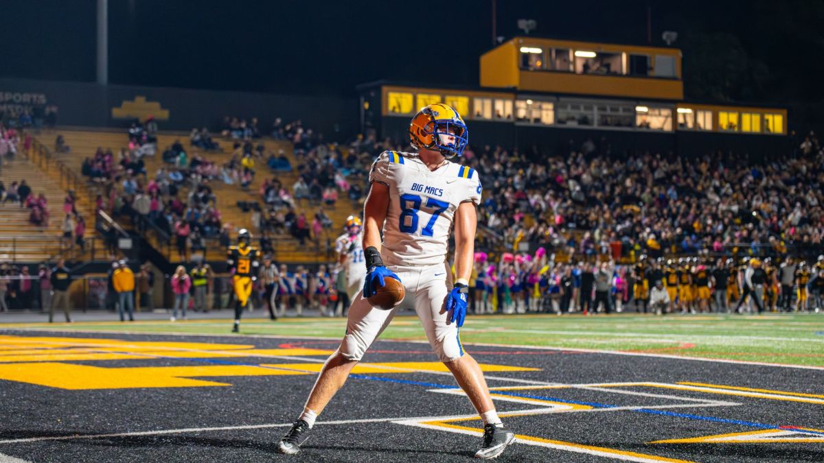 An excited football player celebrates a touchdown during a thrilling night game in a packed stadium.