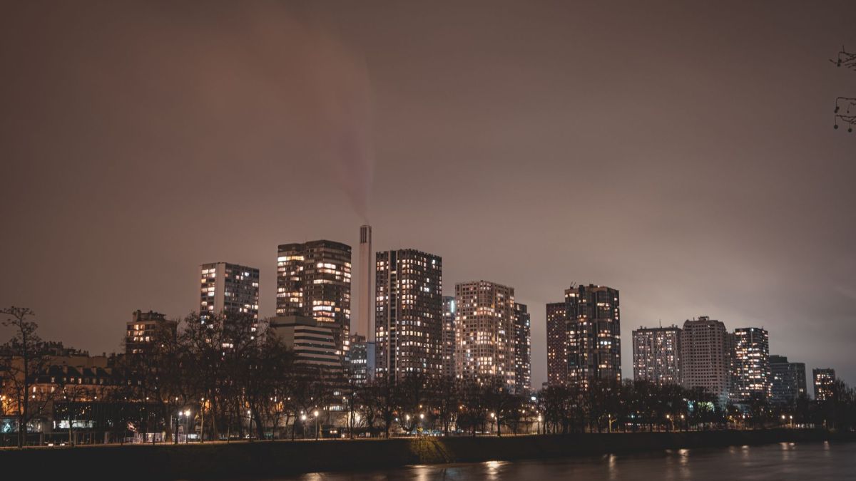 Captivating nighttime view of Paris skyline with illuminated skyscrapers along the river.