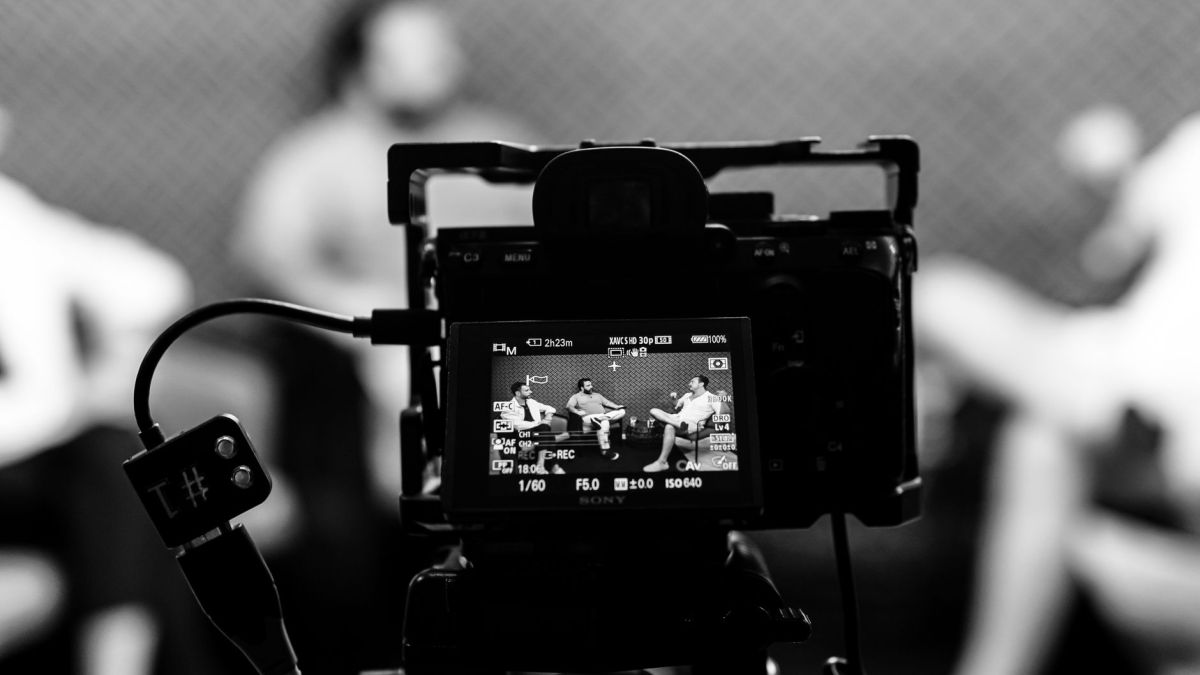 Camera capturing an indoor interview scene, in focus with a blurred background.