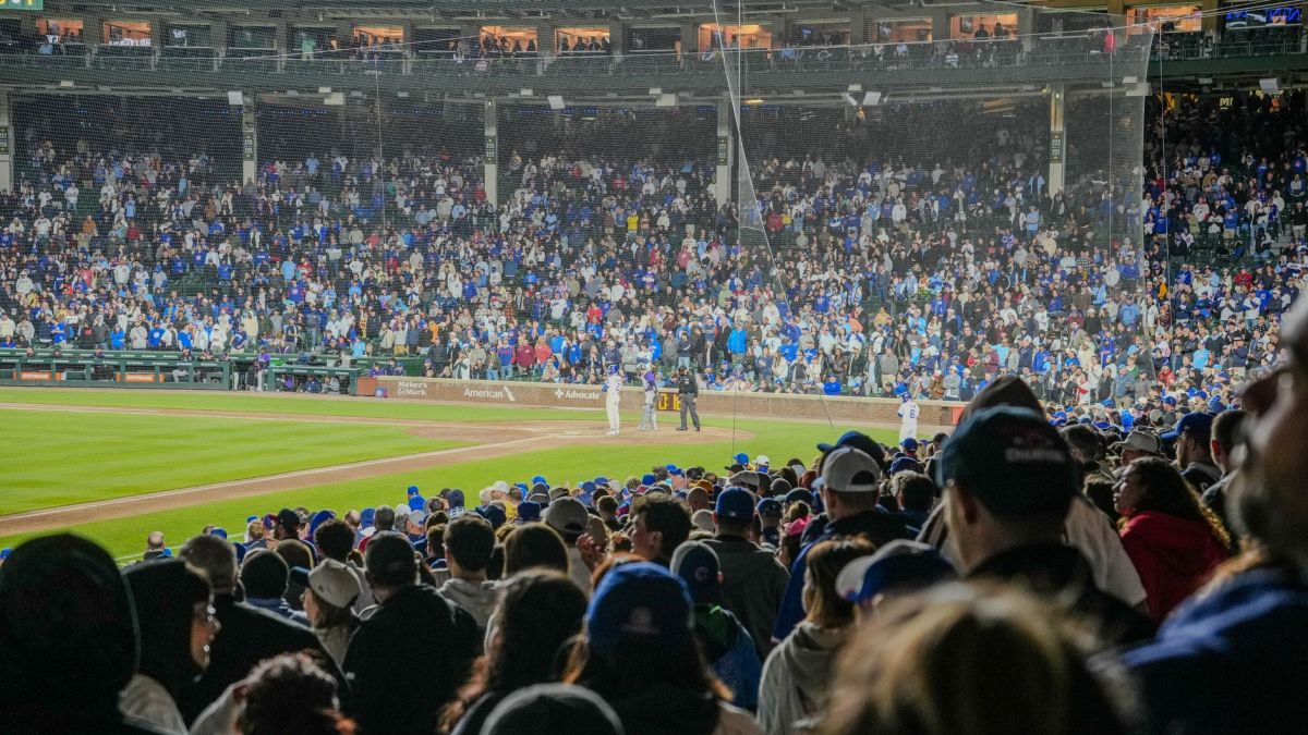 Energetic scene of a nighttime baseball game with a packed stadium crowd.