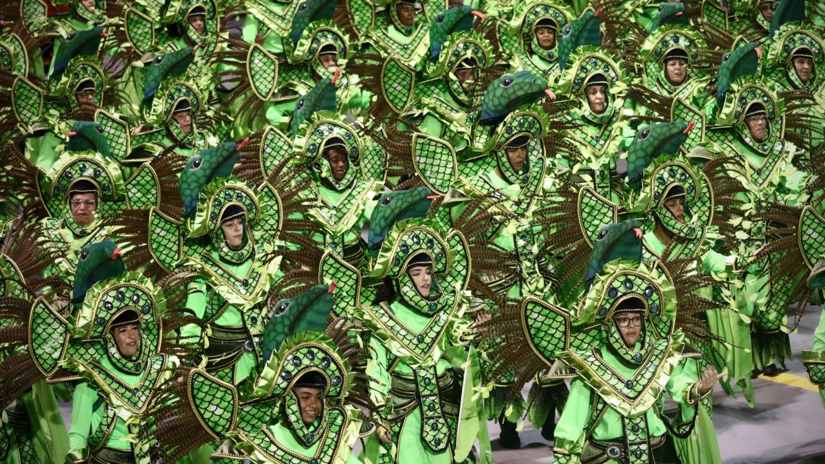 A lively carnival parade featuring colorful costumes with green and bird motifs in Brazil.