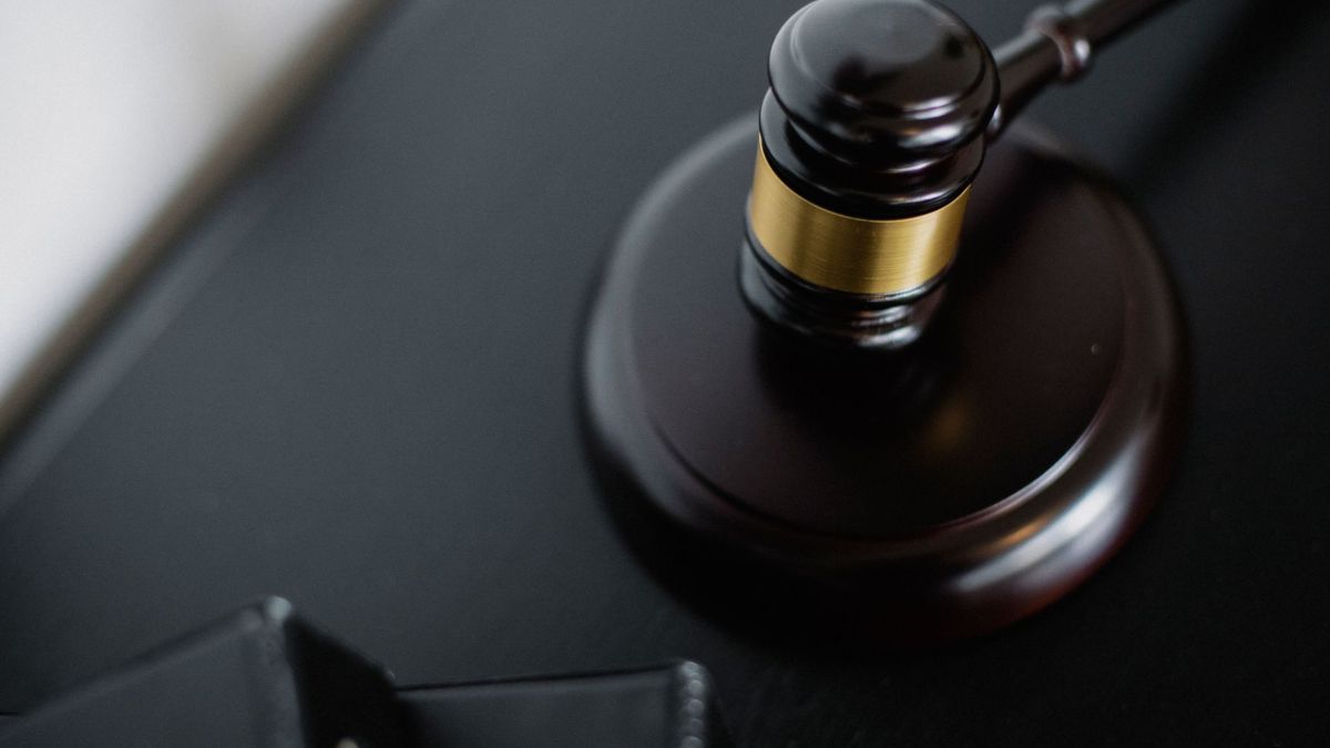 From above of wooden gavel on round surface near folders on table in courtroom