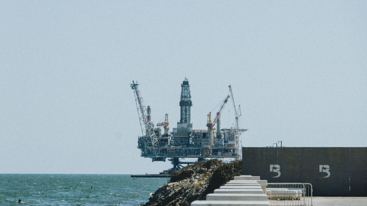 Distant view of an offshore oil rig with cranes on a sunny day.