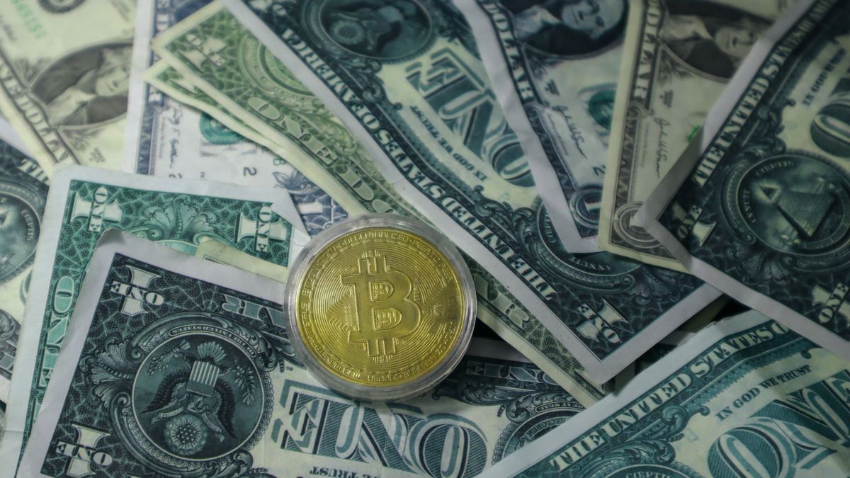 Close-up of Bitcoin cryptocurrency coin on a pile of US dollar banknotes, symbolizing finance and digital currency.