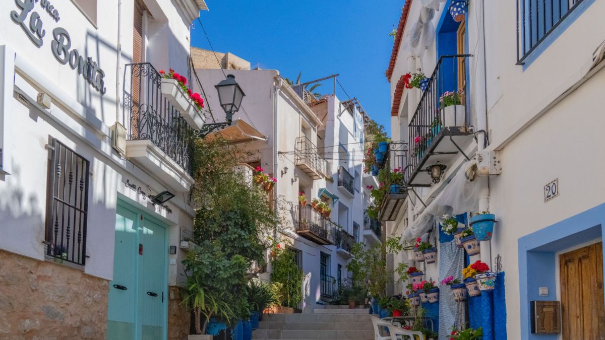 Colorful alleyway in Alicante, Spain, showcasing Mediterranean architecture and vibrant floral decor.