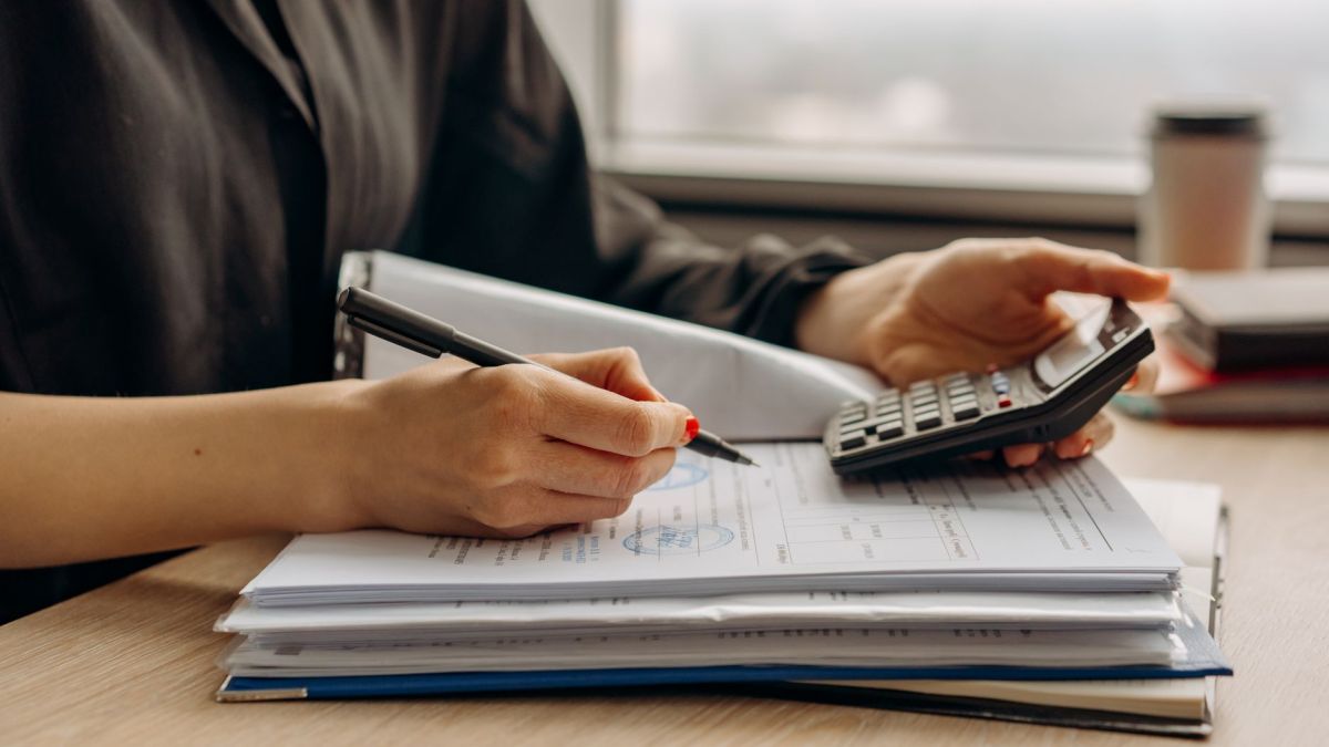 Close-up of person using a calculator with financial documents in an office.