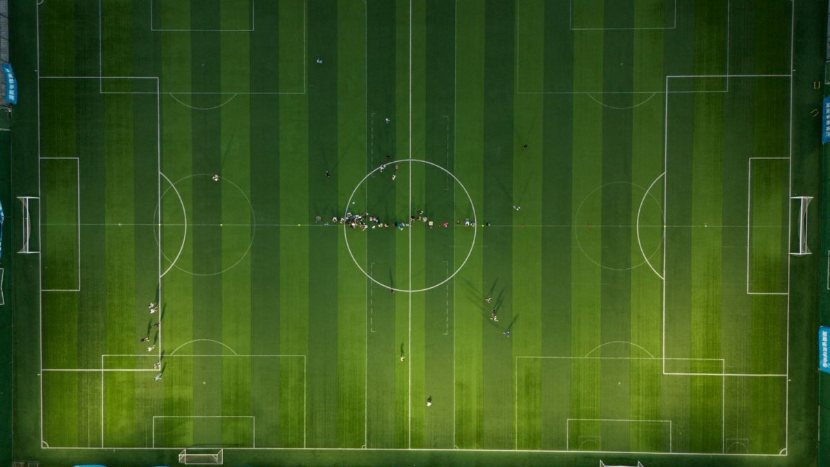 Top-down view of a soccer field with players during daytime.