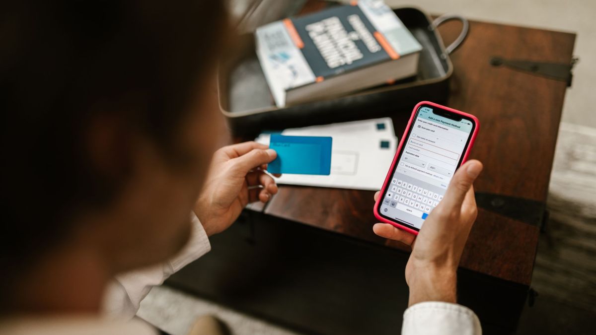 Person making an online payment using a smartphone and credit card indoors.