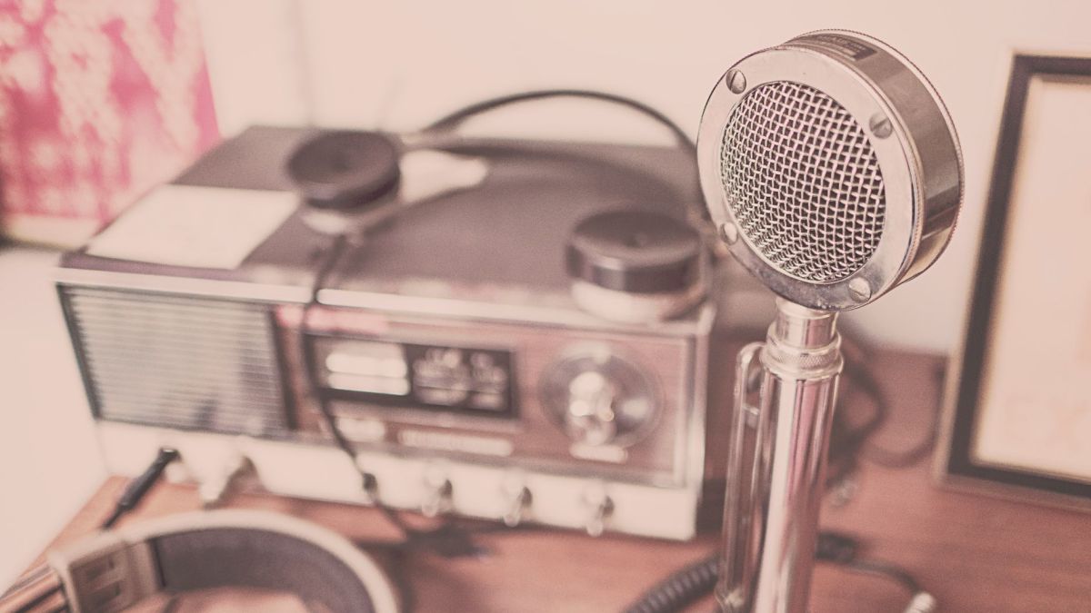 A classic vintage microphone and radio set with headphones displayed on a wooden table.