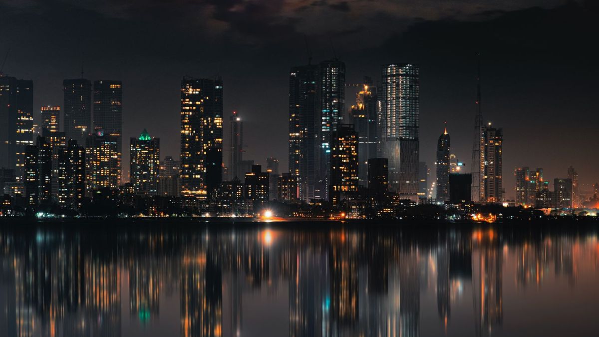 Captivating night view of Mumbai skyline with skyscrapers and reflections on still water.