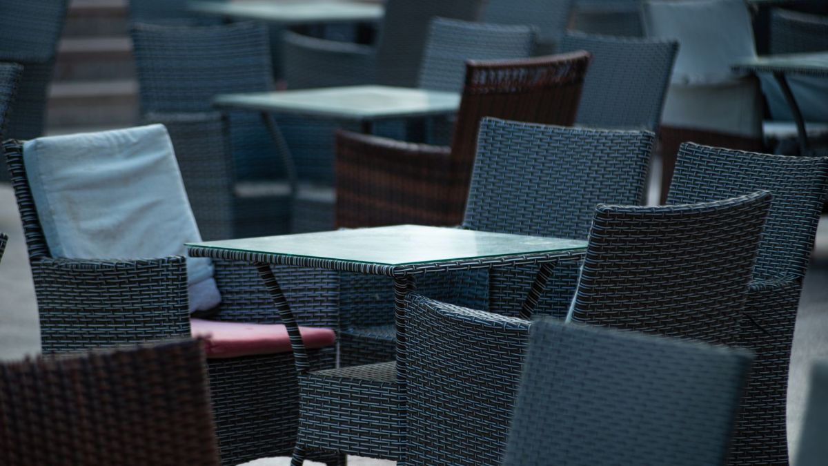 Empty outdoor terrace with wicker chairs and tables, creating a cozy café atmosphere.