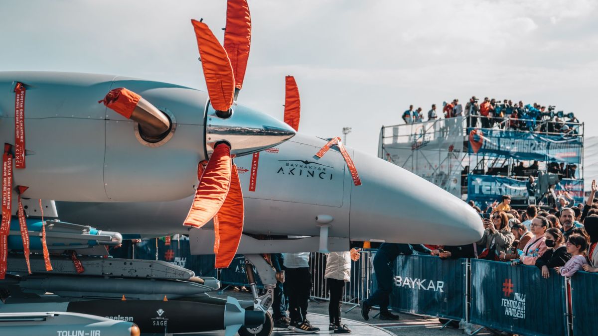 Military drone on display with large crowds at an airshow, showcasing aviation technology.