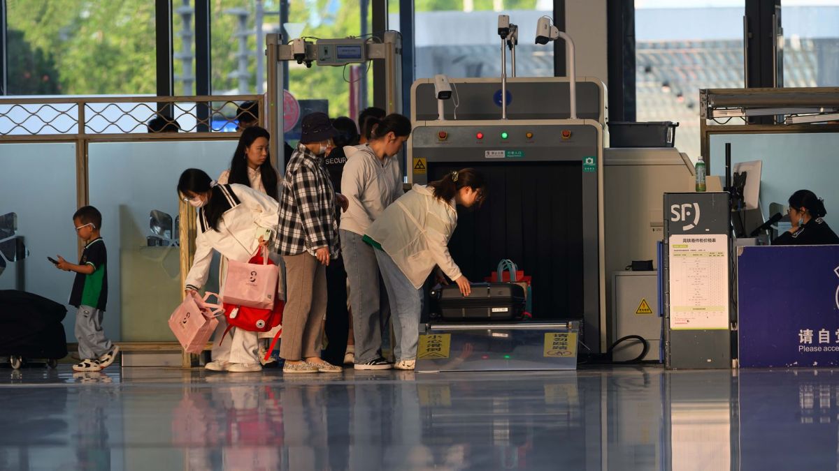 Travelers undergo security screening at an airport terminal.