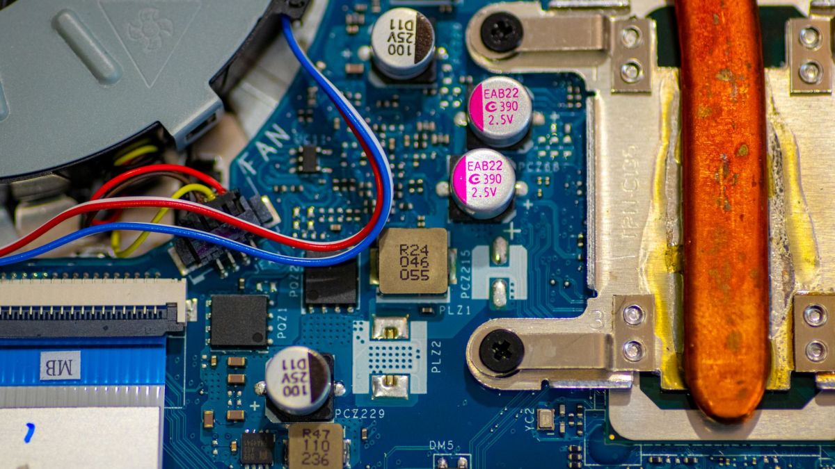 Detailed image showing circuitry and components on a computer motherboard with wires and capacitors.