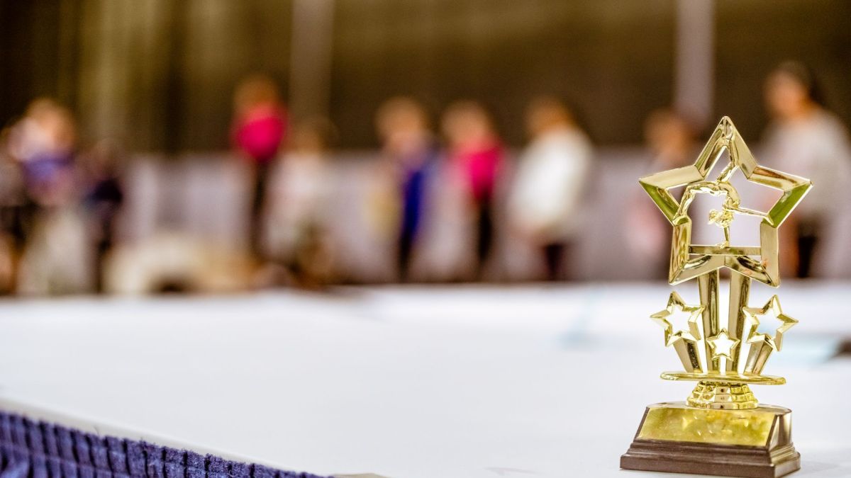 Star-shaped trophy on a table with blurred people in the background at an indoor event.
