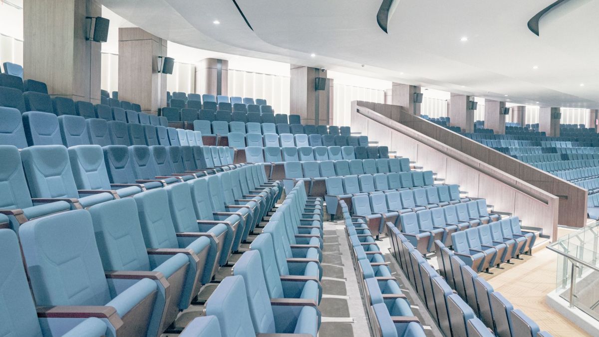 Spacious modern auditorium featuring blue seats and minimalist architecture, ideal for events or presentations.