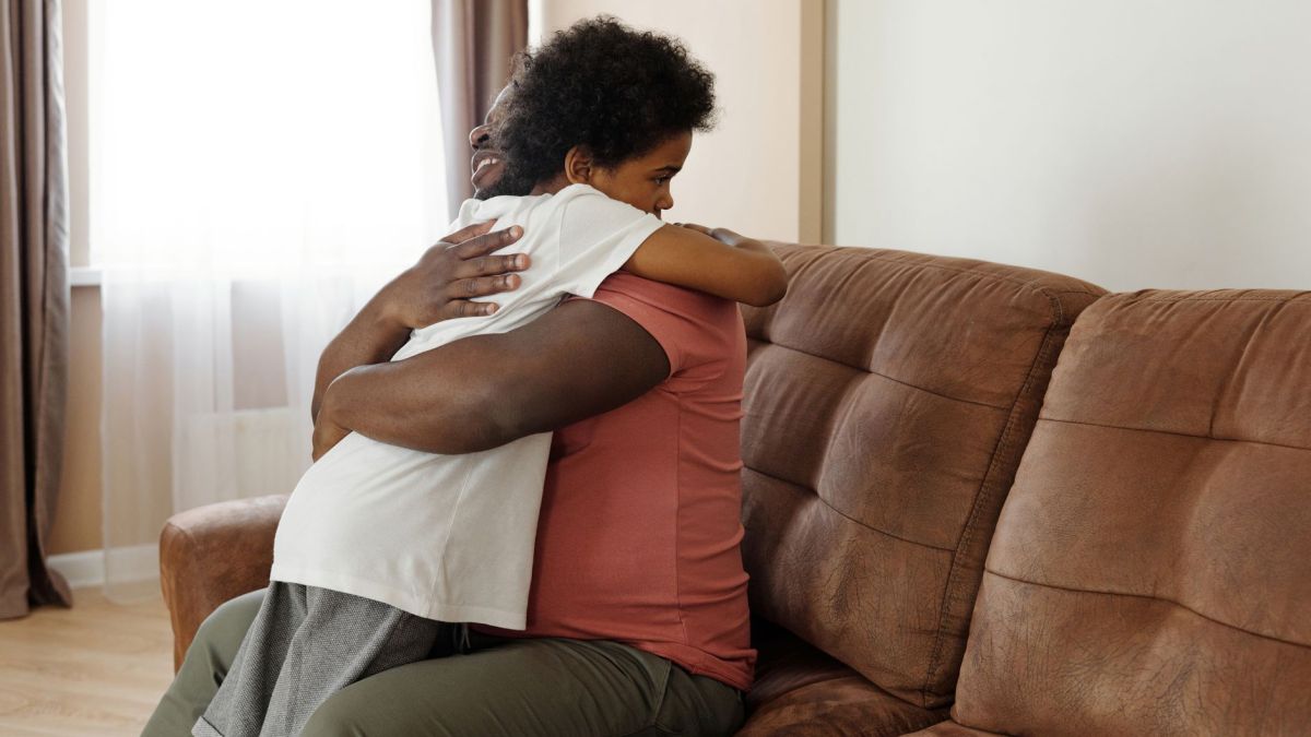 Father and son sharing a warm embrace on the sofa, expressing love and family togetherness.