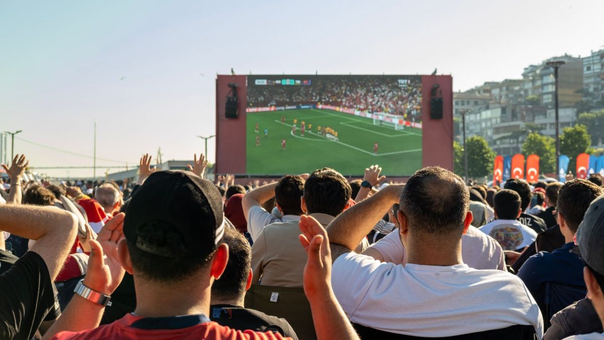Crowd watching a soccer game on a large screen outdoors in Istanbul, Türkiye.