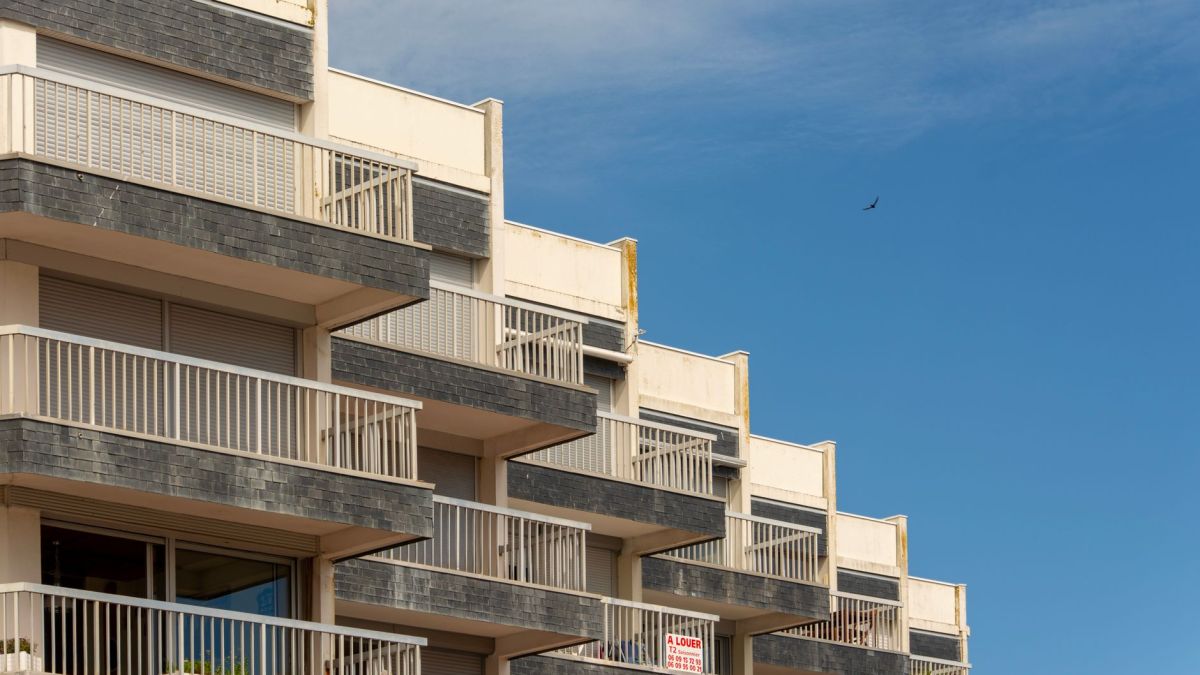 A modern apartment building with distinct balconies against a clear blue sky.