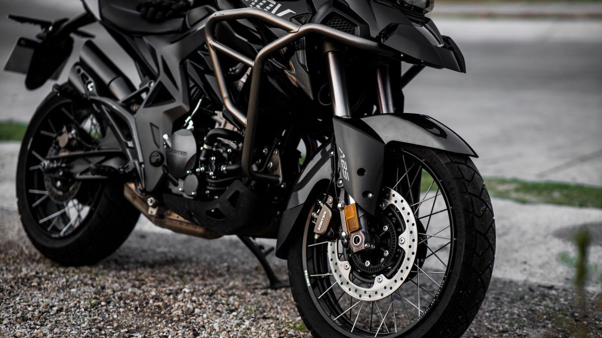 Detailed view of a black motorcycle parked on a gravel road.