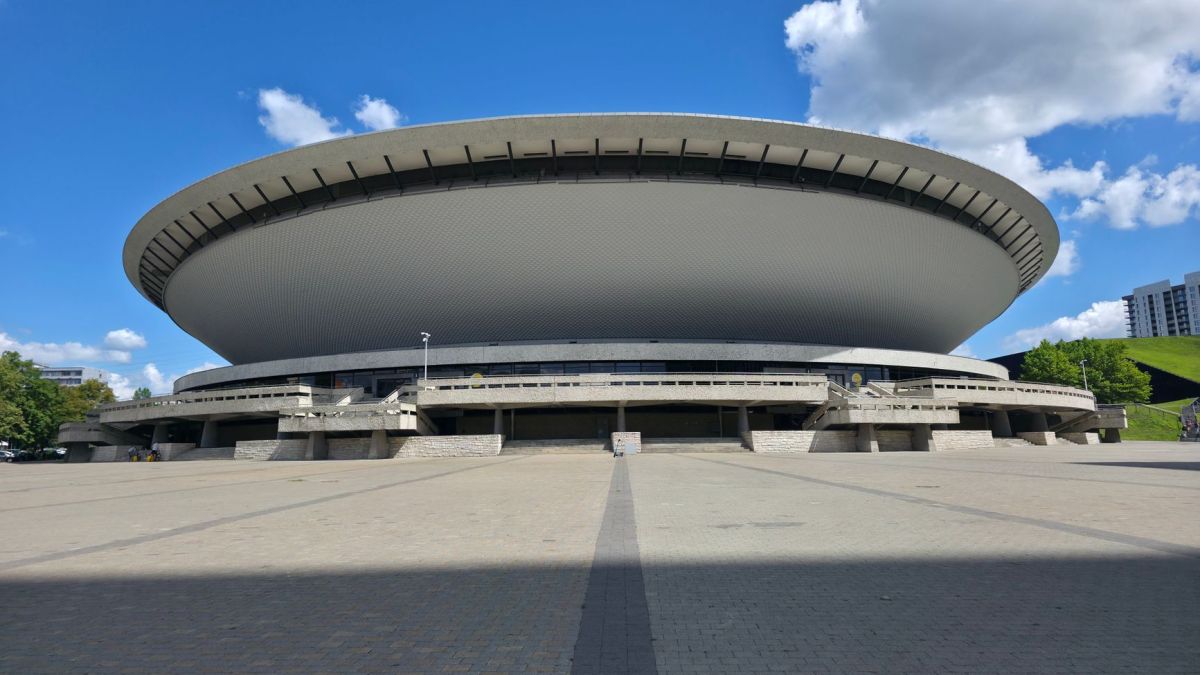 Front view of Spodek Arena in Katowice under a clear blue sky, showcasing its unique architecture.
