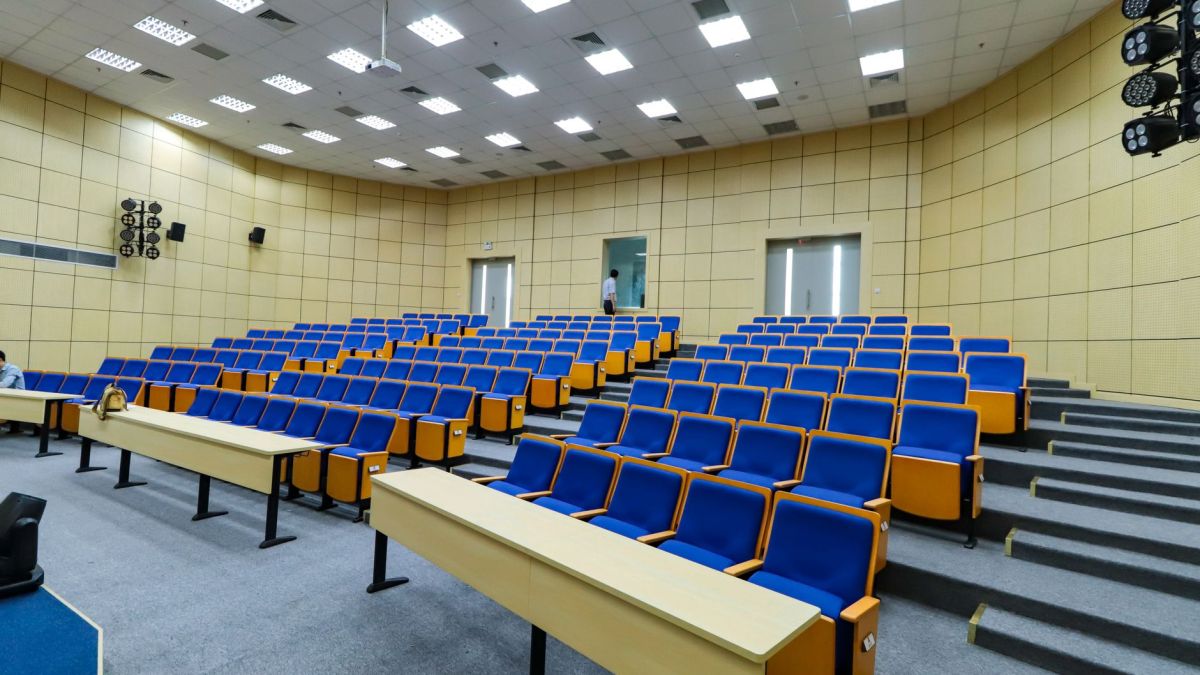 Spacious lecture hall with blue seats and desks ready for students.