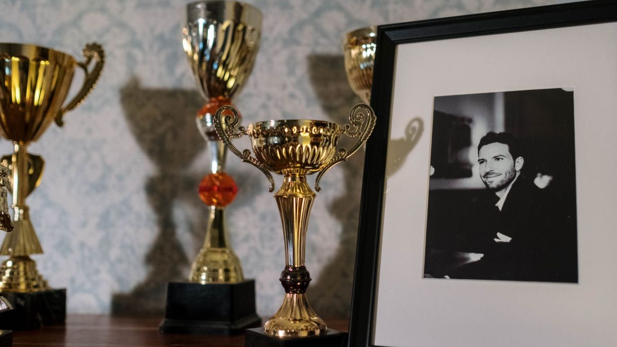 A collection of trophies with a framed black and white portrait on a shelf.