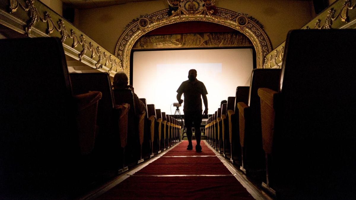 A person walking down an aisle in a vintage theater, showcasing ornate decor.