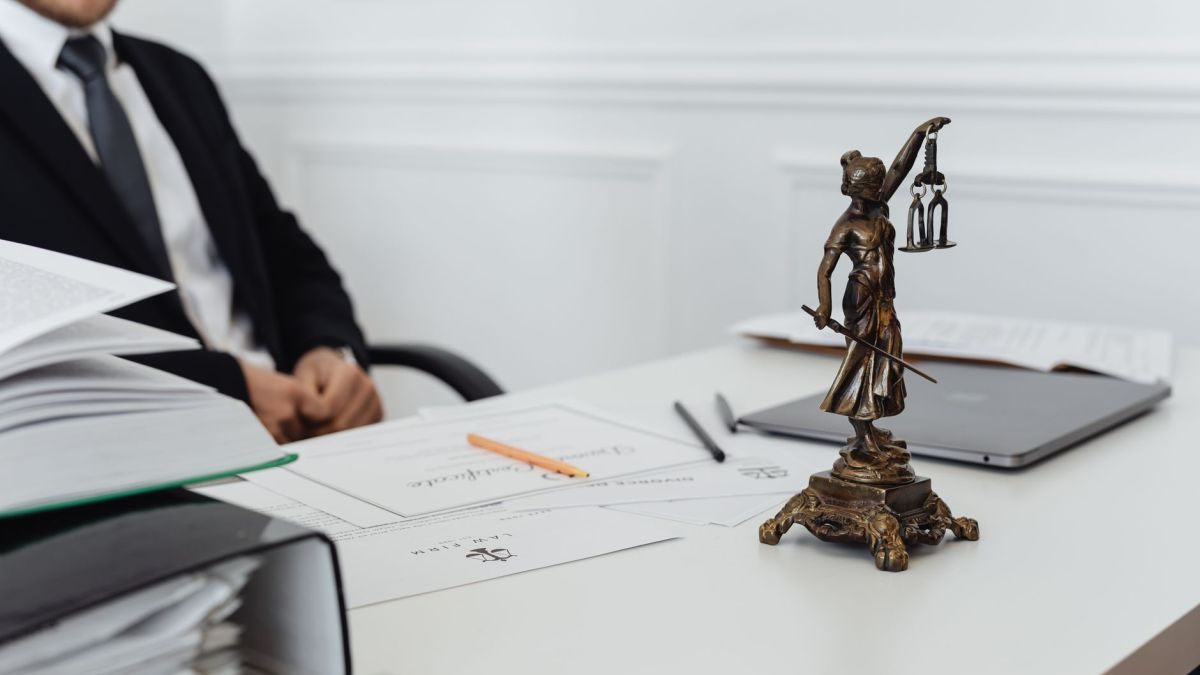 A legal professional's workspace featuring Lady Justice statue, documents, and a laptop.
