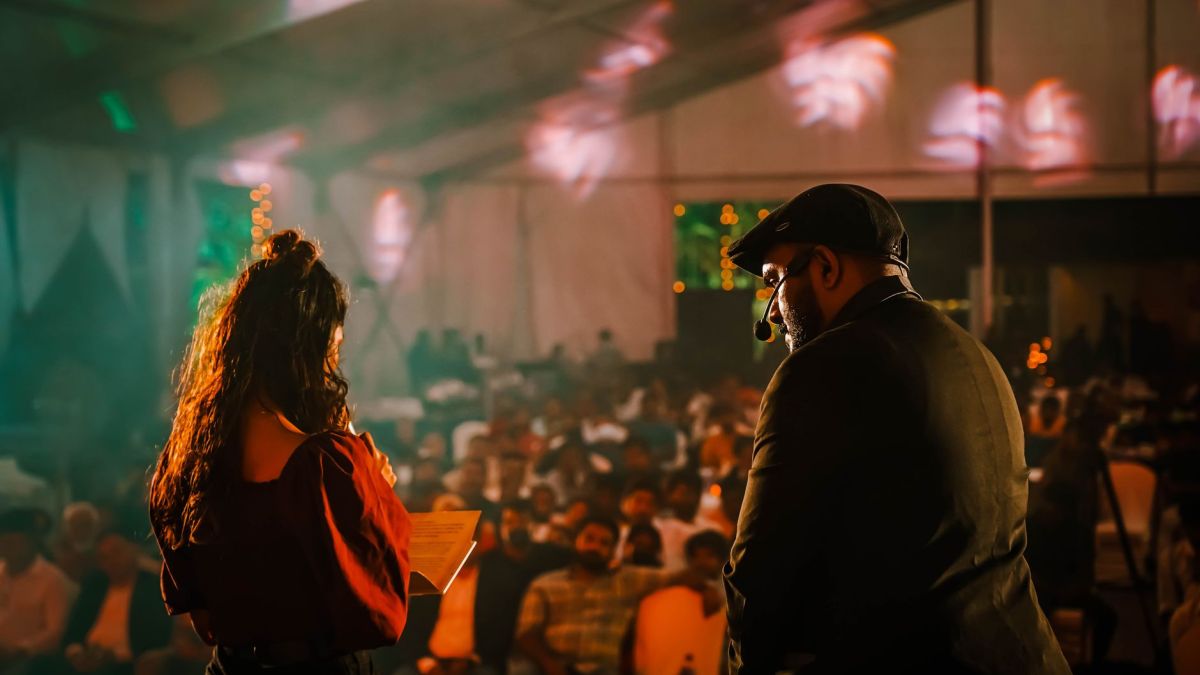 Performers engaging with an audience at a lively indoor event with colorful lighting.