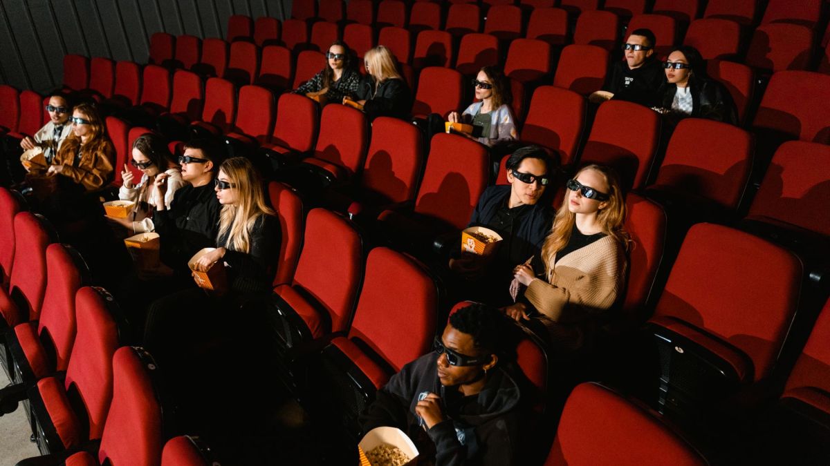 People enjoying a film in a cinema, wearing 3D glasses and eating popcorn.