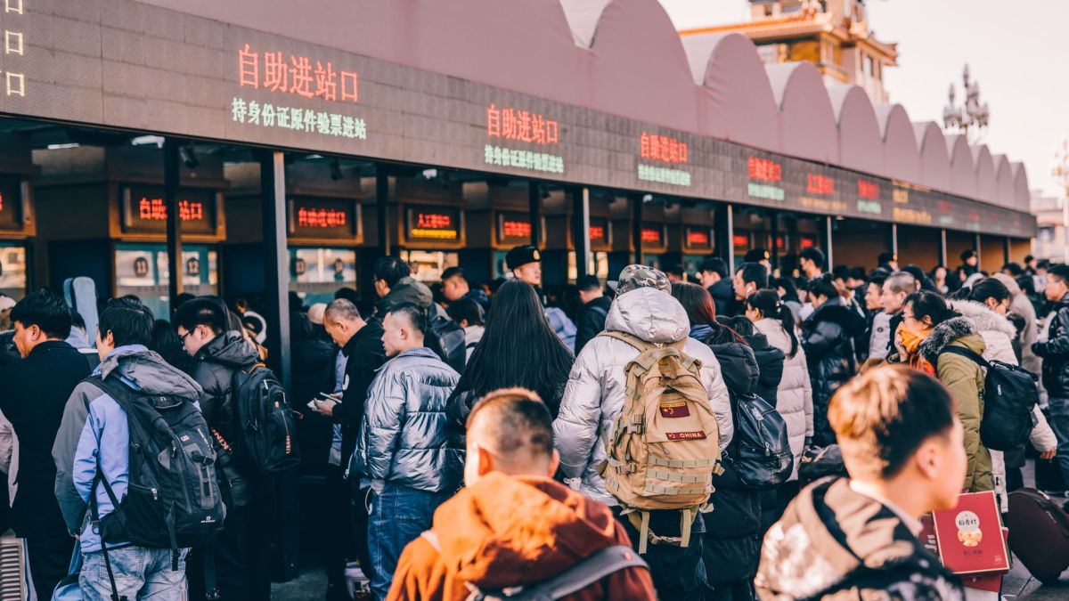 A crowd of people waiting in line at a ticket station in Beijing, China, showcasing modern urban life.