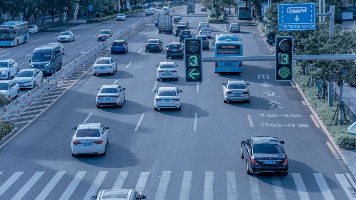 Wide shot of urban traffic at a busy city intersection with cars and buses.