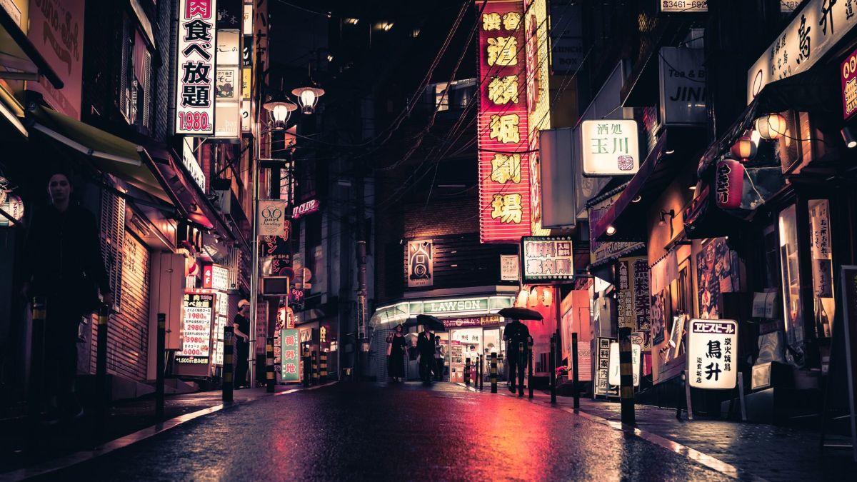 Neon-lit street in Tokyo showcasing urban nightlife, bustling with people and striking signage.